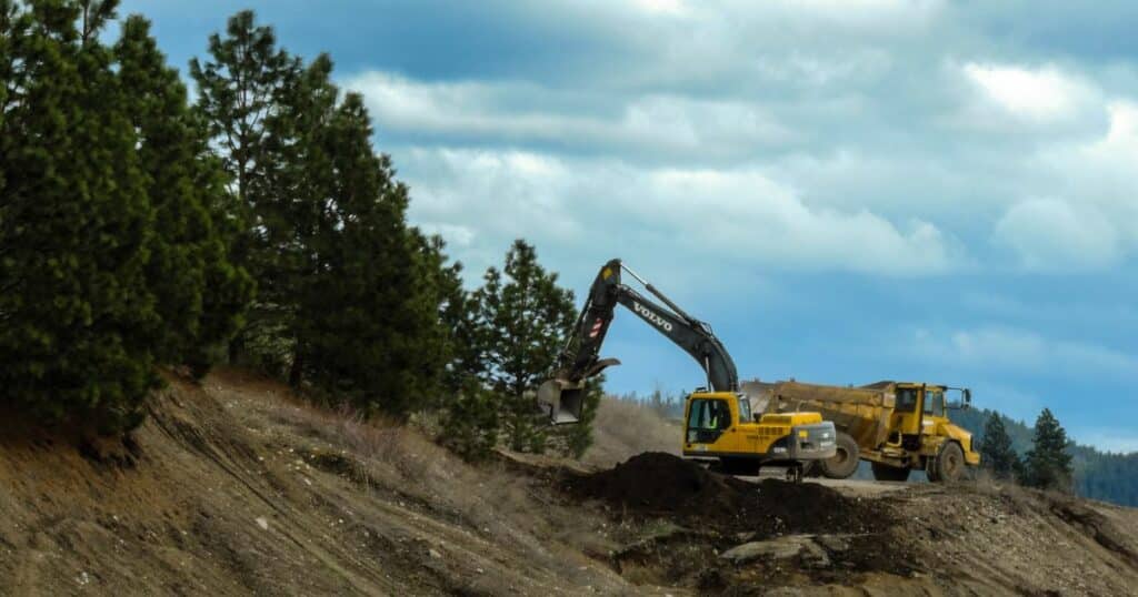 Backhoe cutting down trees resulting in the loss of forests